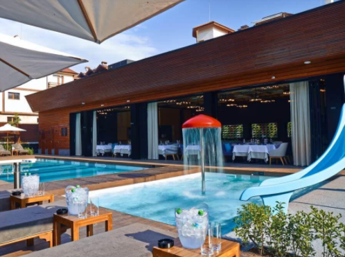 The aqua complex of Lucky Bansko - real water fun for young and old You love the peace and quiet of the mountains, but you love the sea very much and you can't decide where to go during the summer holidays? Do you want to walk on the narrow forest paths of the mountain, but at the same time long for the sea and summer fun on the beach? What if we told you that you can relax in the mountains and at the same time enjoy summer cocktails, sun and endless water fun? If we tell you that everything you need to "bring" the sea to the mountains is in the aqua complex of Lucky Bansko? Aqua complex Lucky Bansko - an endless summer fun at the foot of Pirin The complex will impress you with its refined Mediterranean style, the abundance of greenery, stylish poolside teak tree chairs and tents, the special attitude of the staff and especially with the abundance of water entertainment for young and old. The water entertainment complex of the five-star aparthotel Lucky Bansko is located just meters from the main hotel building. This allows you to put on your swimsuits and flip-flops as soon as you drink your morning coffee and in two minutes you can enjoy the attractions it offers. The water attractions that await you in the aqua complex of Lucky Bansko Two great outdoor pools with mineral water As soon as you step through the entrance of the aqua complex, two outdoor mineral pools await you - one for children and one for adults. The adult pool has a depth of 1.45 to 1.60 cm, and the water in it is maintained at a temperature of 29 degrees. Around the pool are luxurious sun loungers and tents where you can sit and enjoy the warm sun while tanning. While you are relaxing, you will be taken care of by impeccably trained waiters, ready to fulfill your every wish for cocktails, snacks or something sweet. And when you decide to swim in the pool, your senses will be pampered with professional music sound, music from which you can listen even when swimming underwater. The children's pool has a depth of 0.57 m and is suitable for children up to 7 years. You do not have to worry that if the children stay longer in the pool they can catch a cold, as the water is maintained at a constant temperature of 29 degrees. This is the perfect temperature for endless water fun, so you can safely let them have fun while you drink your favorite cocktails and sitting comfortably on sun loungers or under tents. Children's water attractions Lucky Bansko knows that children love not only the fun in the pools and water attractions. Therefore, especially for the little ones (and their slightly older brothers and sisters) there is a fun and crazy water slide, mushrooms with water effects and many other water entertainments by the pool. Be sure that once your children see the attractions, they will not want to get out of the water. Going down the water slide is a real pleasure for the little ones and they will have a really great time, and if the games under the mushrooms and other water attractions start, it will be very difficult to get them out of the pool even to relax and eat something. And while you and your children have fun in the pools, your safety will be taken care of by qualified lifeguards who are ready to intervene in case of need. Great Italian restaurant If you are hungry, you do not need to look for a place to have lunch or dinner. You do not even have to leave the aqua complex, as there is one of the best Italian restaurants not only in Bansko, but in all of Bulgaria. Leonardo Restaurant serves authentic Italian cuisine, the products of which are delivered directly from Italy. The atmosphere in the restaurant is Mediterranean, the food - extremely tasty, and the wine will take you to the beautiful and sunny Tuscany. Here you can eat fragrant pasta, pizza, risotto with seafood, tender lamb chops, Caprese salad, gelato, panna cotta or order the chef to prepare a special dish for you. If you don't want to get up from the deck chairs to eat, you don't have to. Just order what you like and the waiters will serve you the selected dishes directly at the pool. Special treatment and additional services To visit the aqua complex, you do not have to be a guest of Lucky Bansko Aparthotel. The complex is open to all visitors who for a symbolic entrance fee per day receive a deck chair or tent, umbrella, table, towel and a bottle of mineral water. Each visitor who has paid the entrance fee can take advantage of all services and water attractions on the territory of the entertainment complex and stay as long as he likes (or until the closure of the aqua complex). You can also take advantage of a 50% discount if you visit the complex on weekdays. And especially for all regular visitors, the water entertainment complex offers the option of "preserving a deck chair", and for this purpose the lifeguards of the pool must be notified in advance. The complex is open from July to September and is open from 10.00 to 20.00 (no day off). The aqua complex of Lucky Bansko - the place where the sea comes by the mountain Are you looking for the perfect place for a family vacation that can offer you both the summer coolness of the mountains and the water fun and attractions of the sea? In Lucky Bansko Aparthotel you will find everything you need for a perfect vacation. The five-star hotel has luxuriously furnished studios and apartments where you can relax, with a luxurious SPA, gym and several restaurants that offer food that is a real pleasure for the palate. And just a few steps from the main hotel building, the aqua complex can provide you with summer water entertainment that will make you forget that you are far from the sea. You don't have to go to the sea when it comes to you. In the aqua complex of Lucky Bansko you will find the endless water fun that you long for and you will return home rested, full of energy and with an exceptional tan, which will be envied even by those who have rested on the beach.