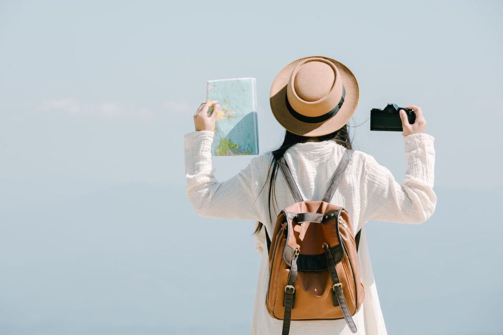 жена с шапка в гръб държи в ръцв фотоапарат и карта