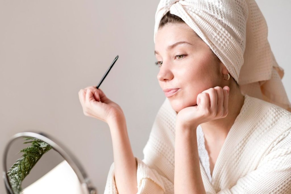 жена с красива кожа се гледа в огледалото и се усмихва