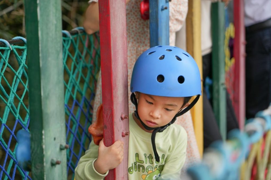 Малко дете с каска на съоръжение за катерене