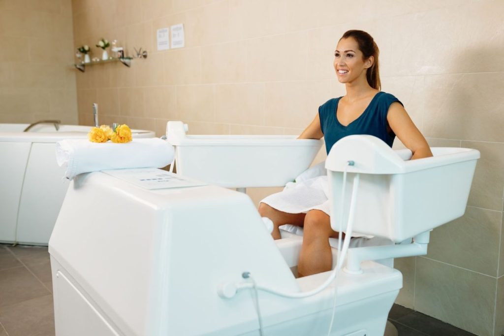Жена е седнала в специална вана за хидромасаж в спа център.